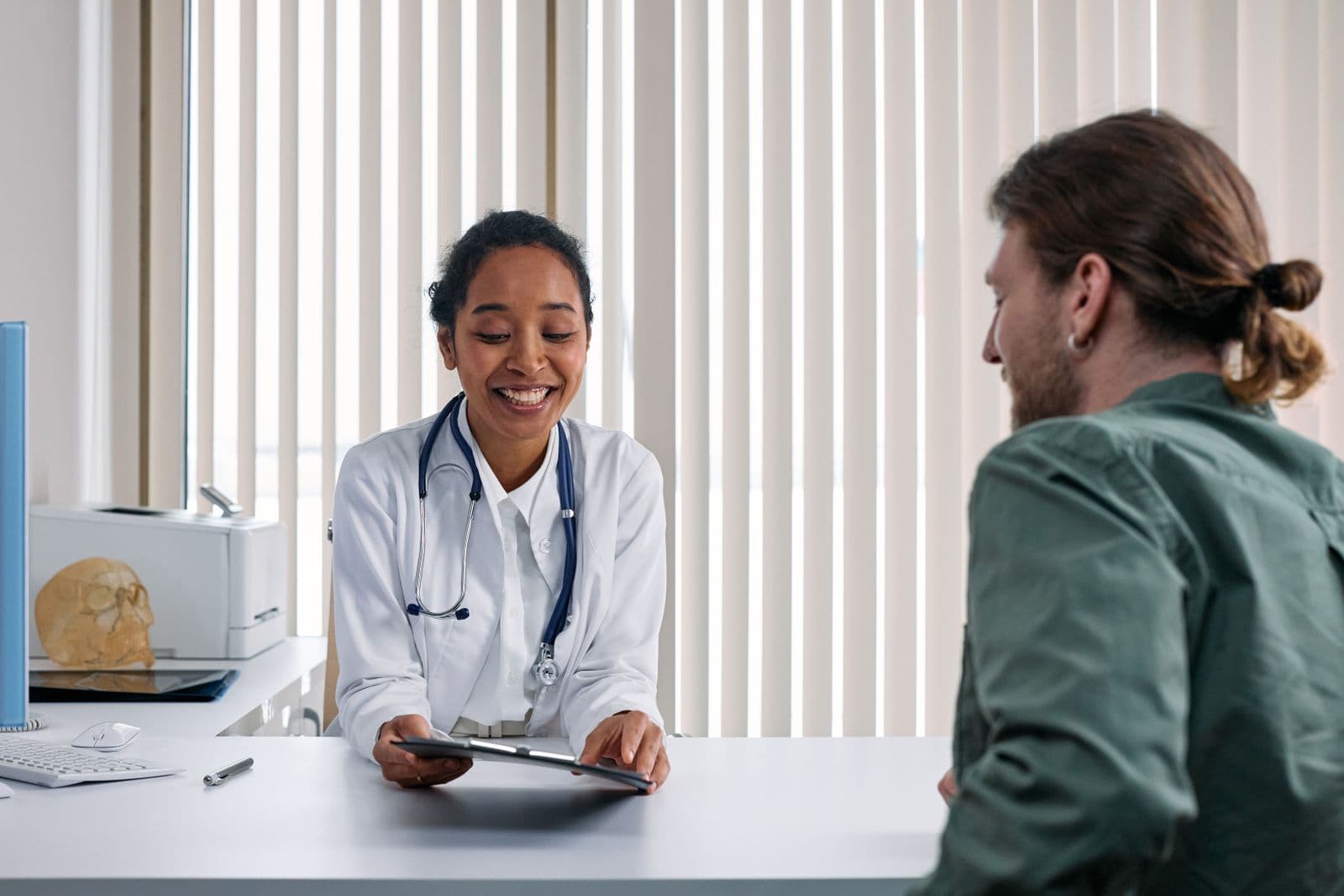 Médica em consulta, conversando com a paciente sem olhar para a tela do computador
